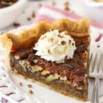 A slice of maple pecan pie topped with whipped cream