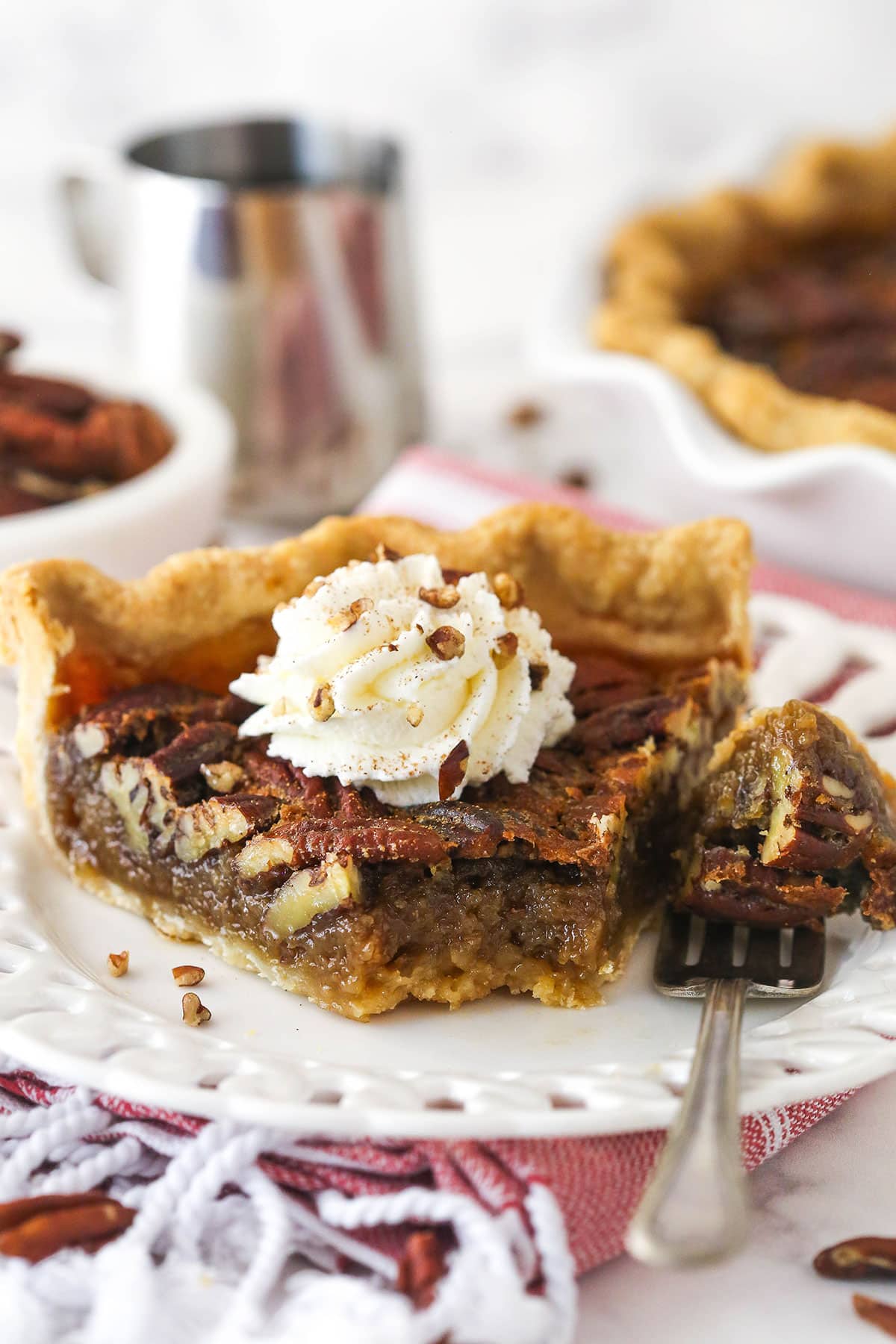 A slice of maple pecan pie on a white plate with a dollop of whipped cream