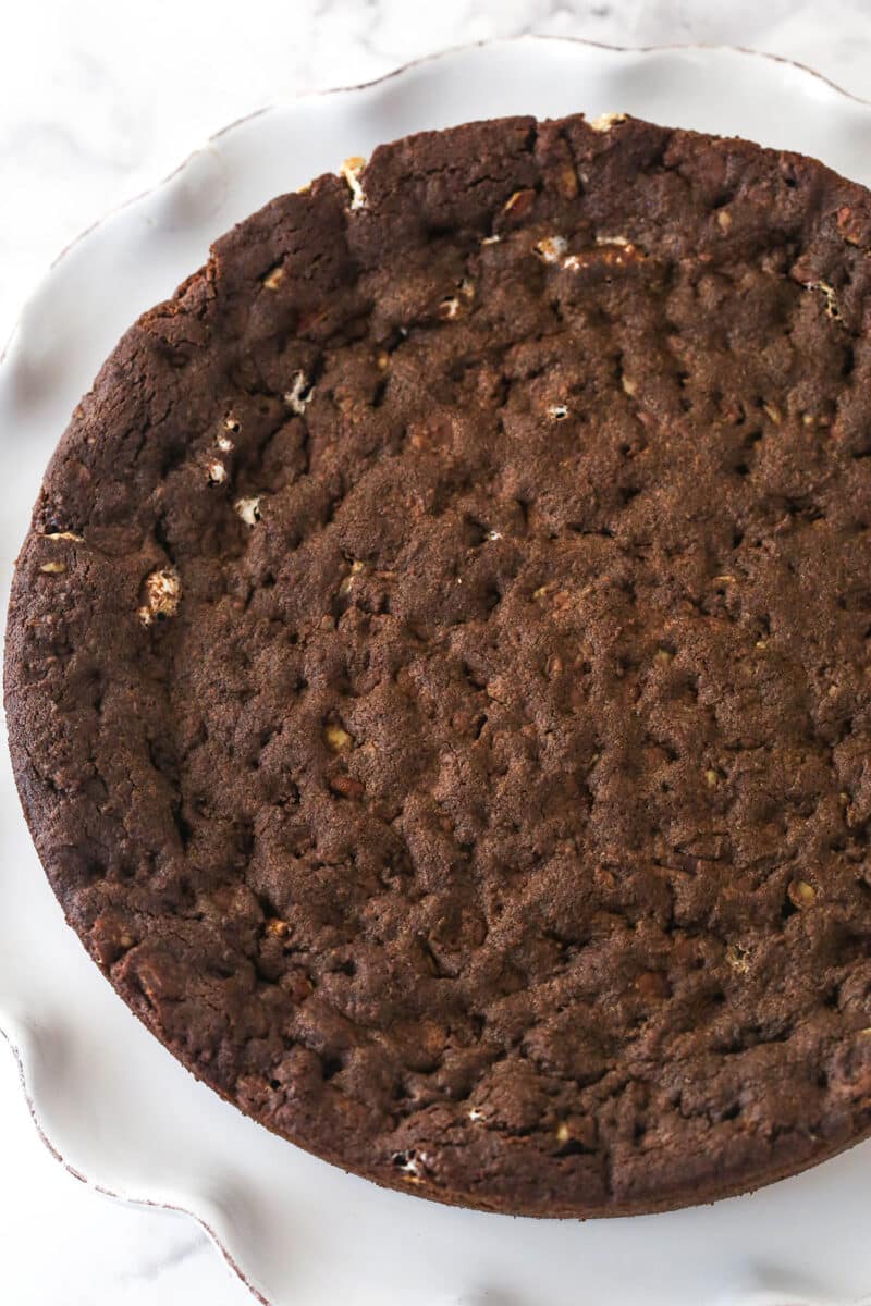 A baked Rocky Road Cookie Cake on a white ruffled cake plate.