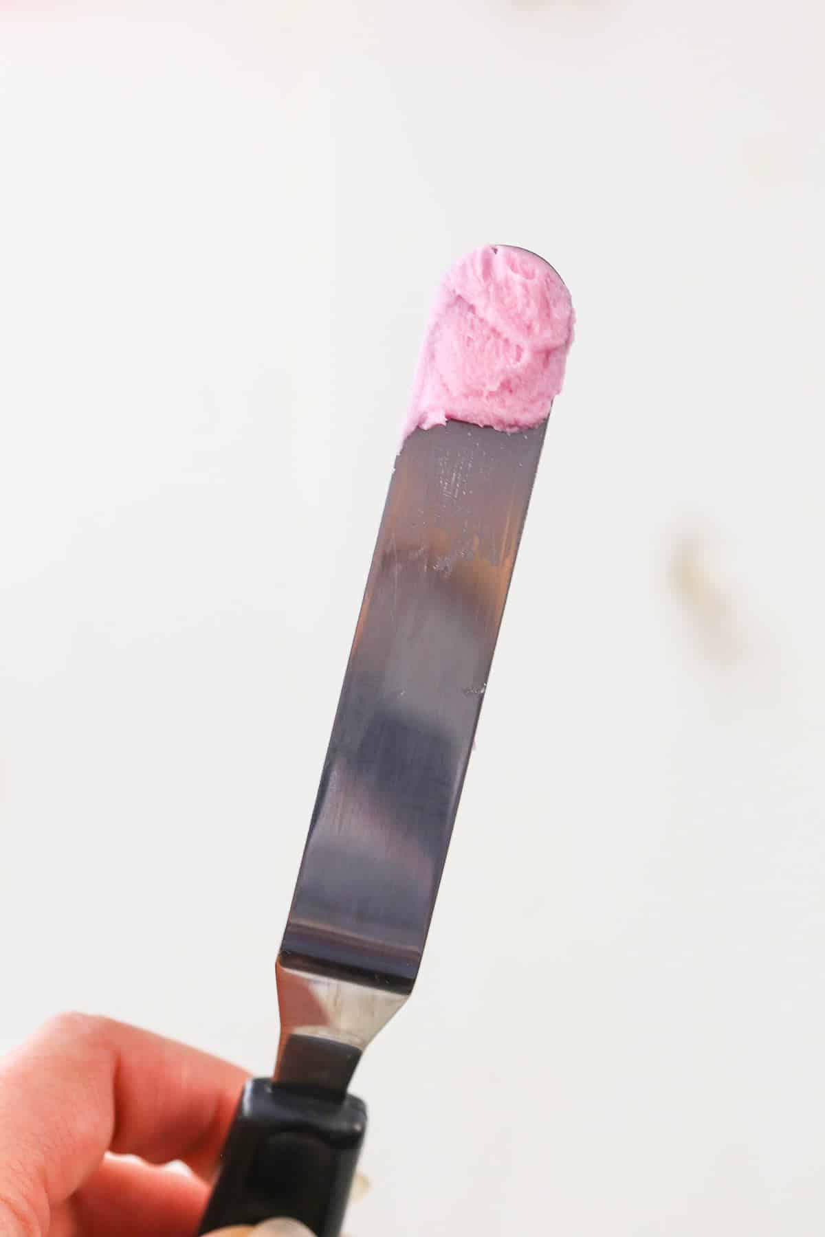 Pink frosting on the tip of an offset spatula