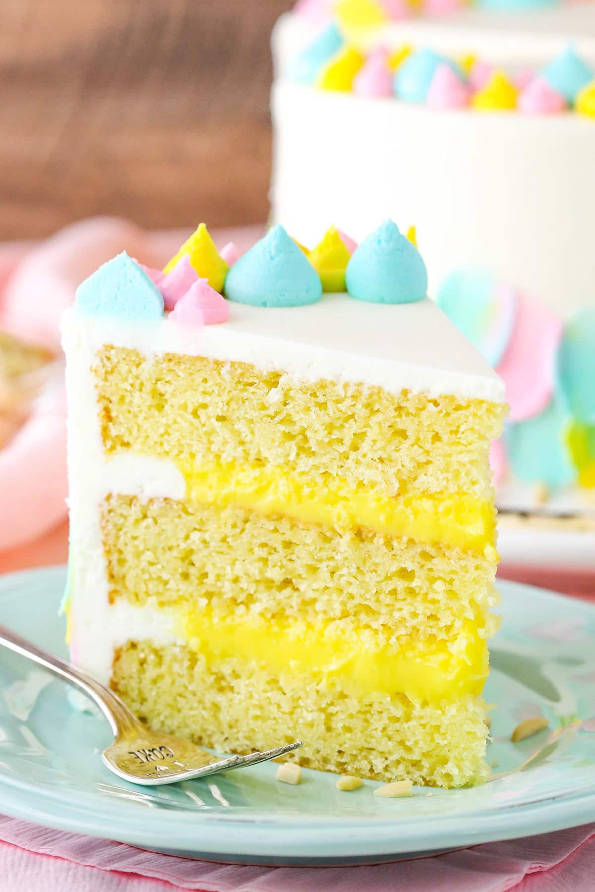 A slice of Almond Custard Layer Cake next to a fork on a light blue plate