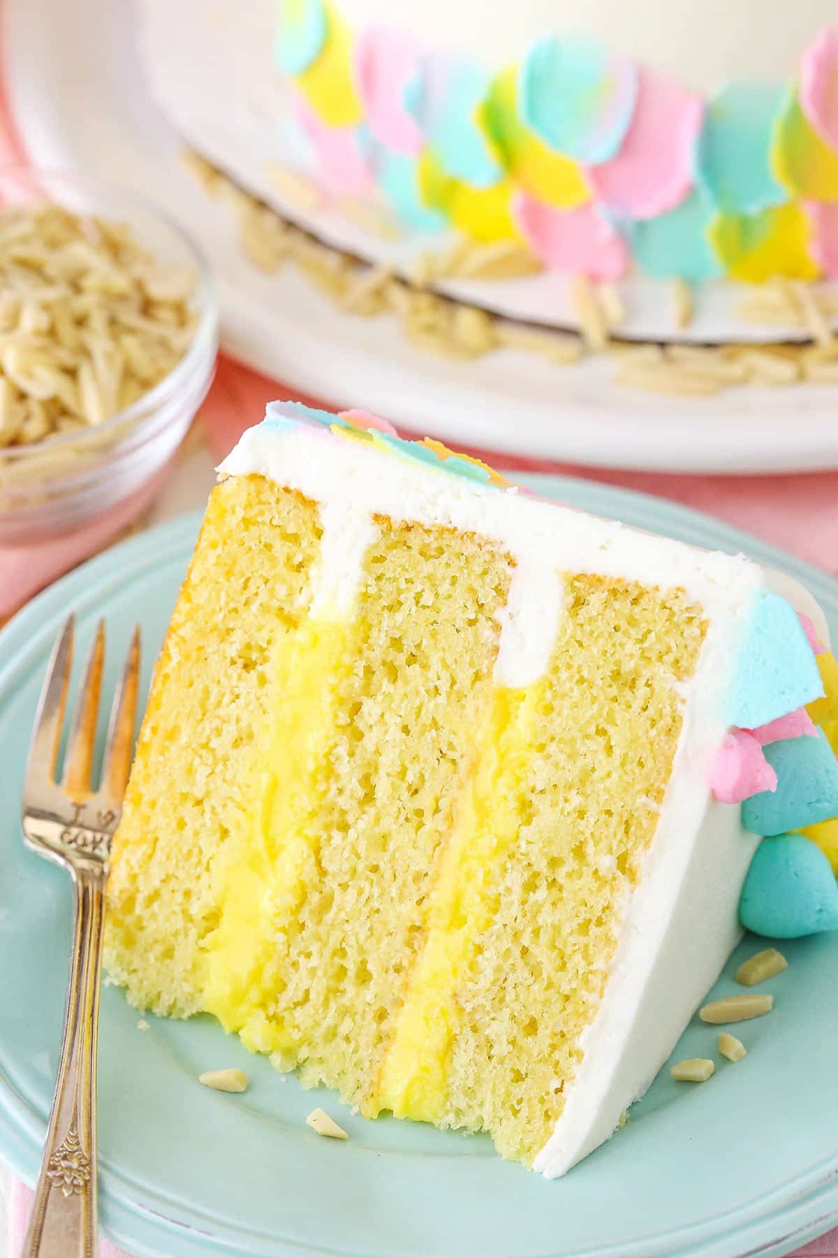 A slice of Almond Custard Layer Cake next to a fork on a light blue plate