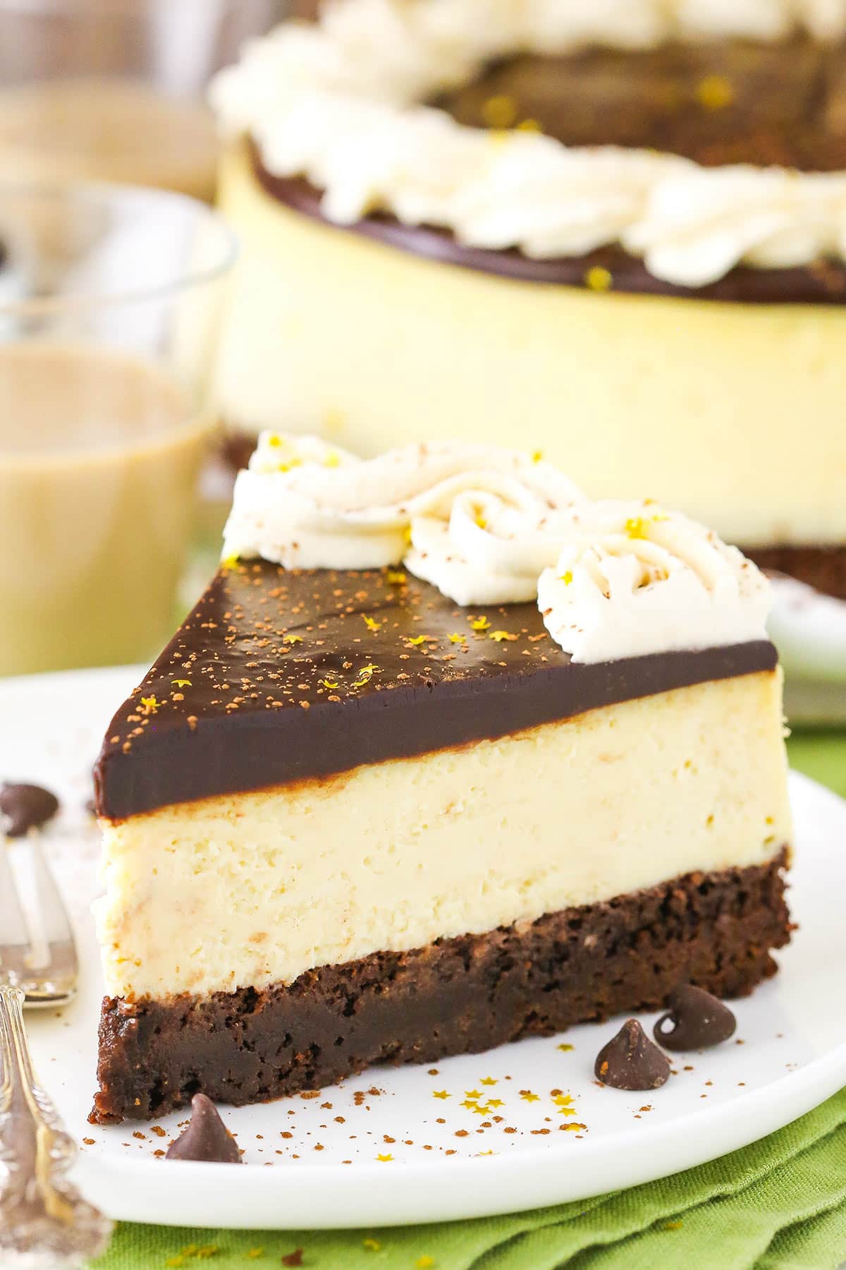 A slice of Baileys Brownie Cheesecake next to a fork on a white plate