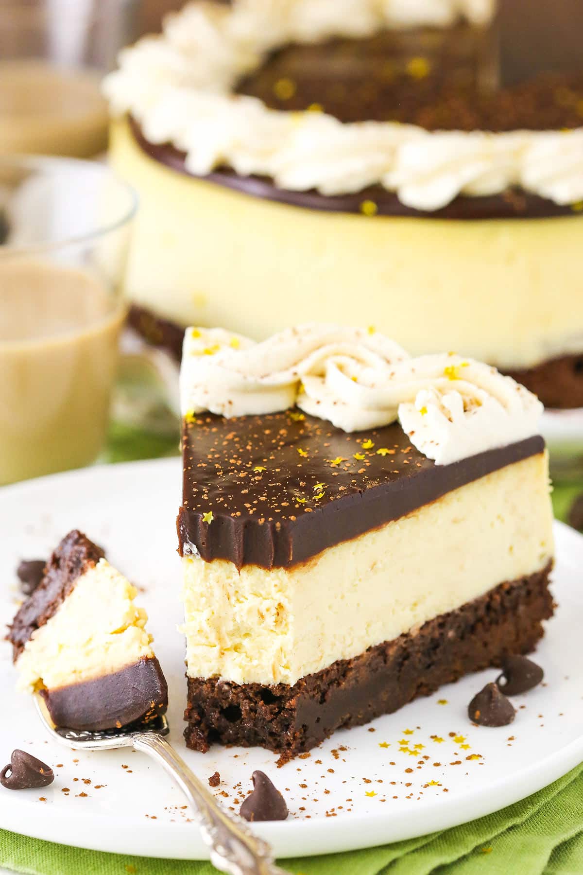 A slice of Baileys Brownie Cheesecake with a bite removed next to a fork on a white plate