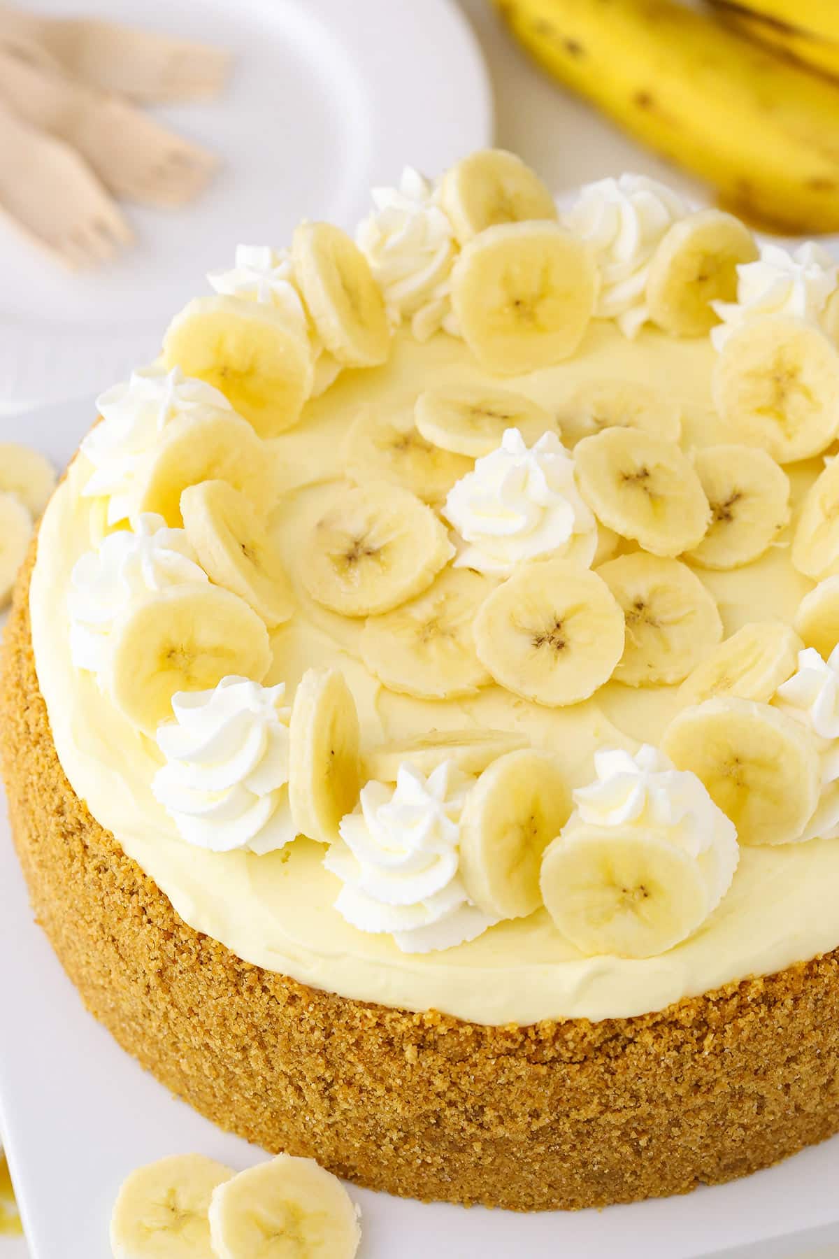 Overhead view of a full Banana Cream Cheesecake on a white cake stand