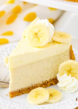 A slice of Banana Cream Cheesecake next to a fork on a white plate