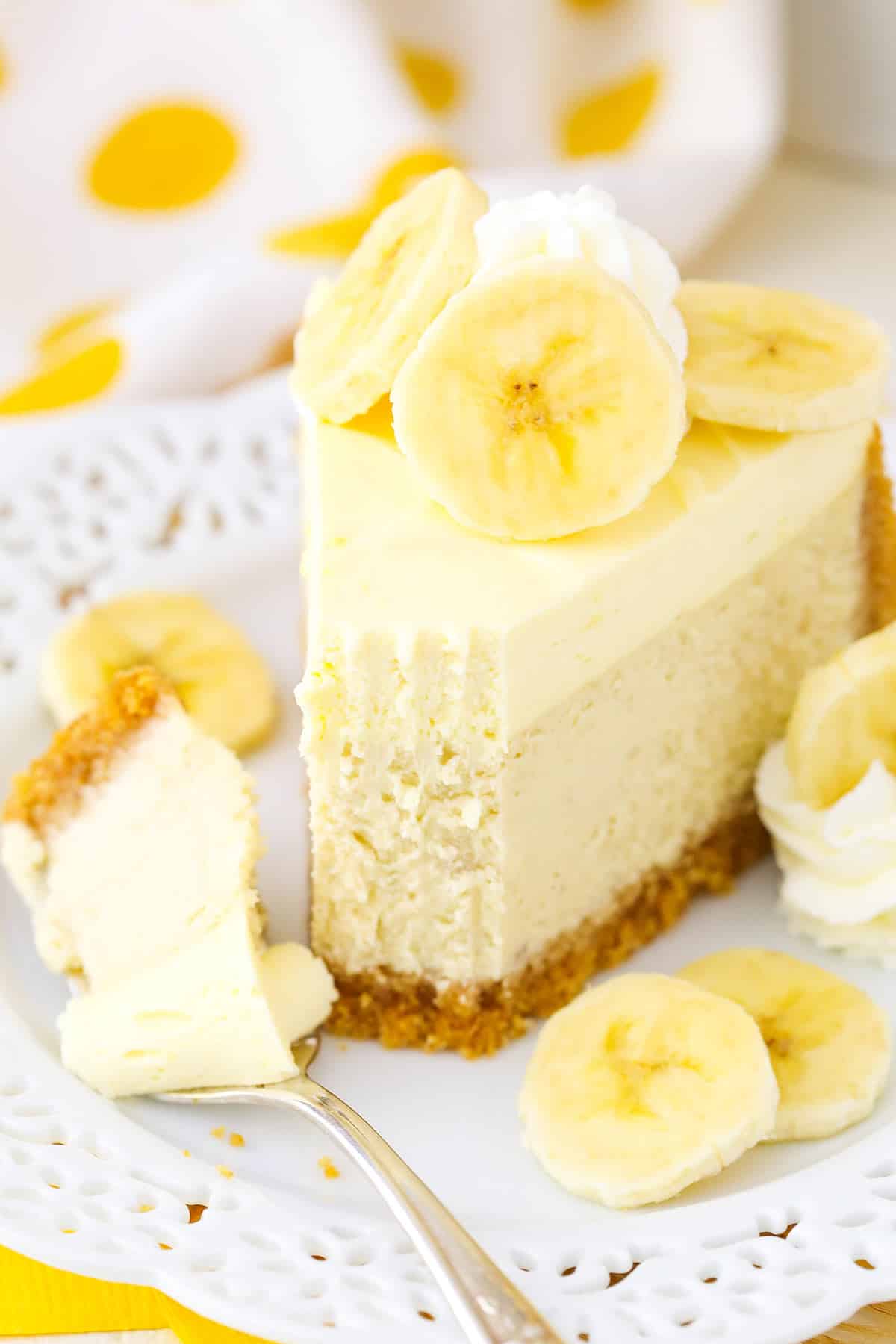 A slice of Banana Cream Cheesecake with a bite removed on a white plate