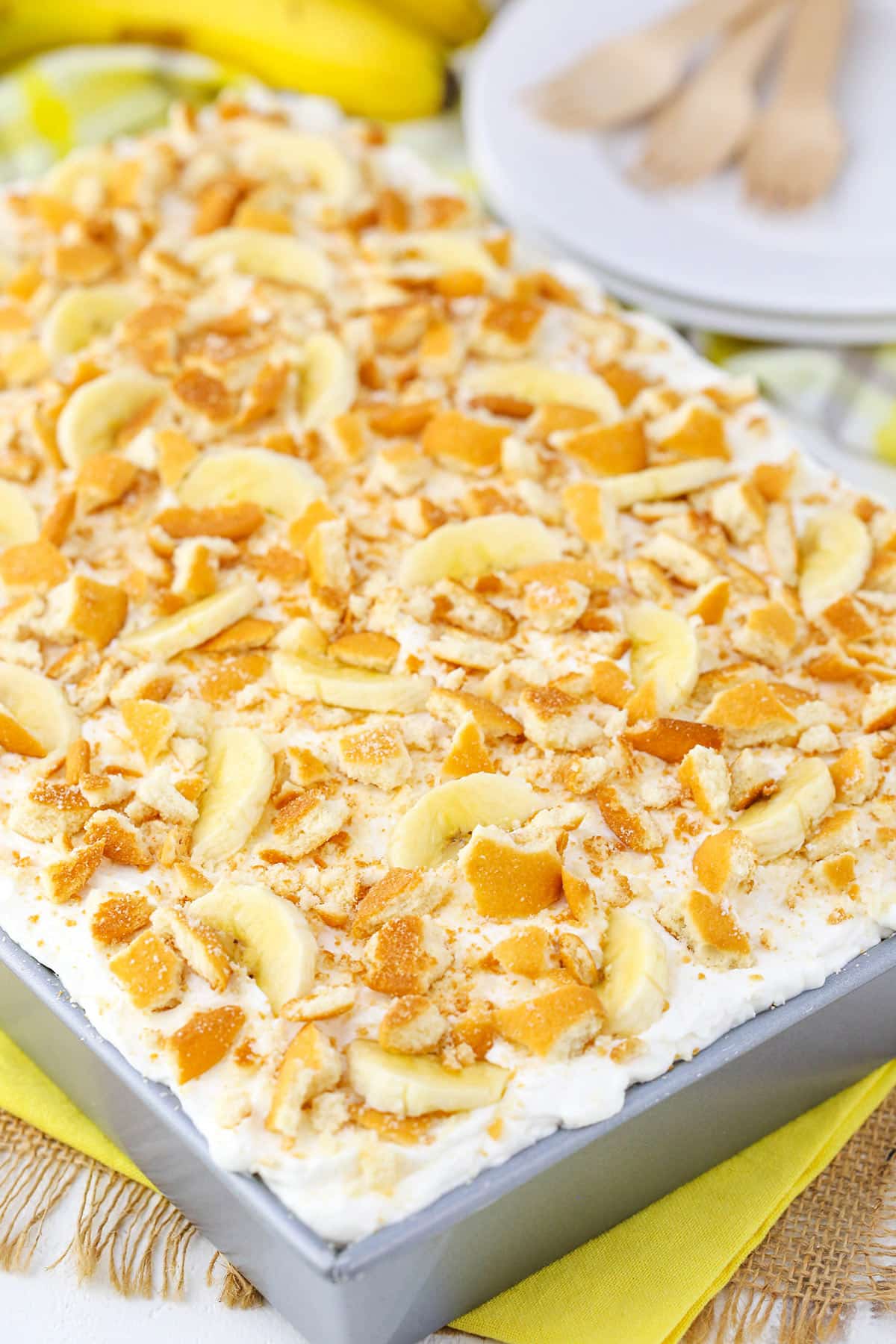 A full Banana Pudding Poke Cake in a gray cake pan on a yellow table cloth