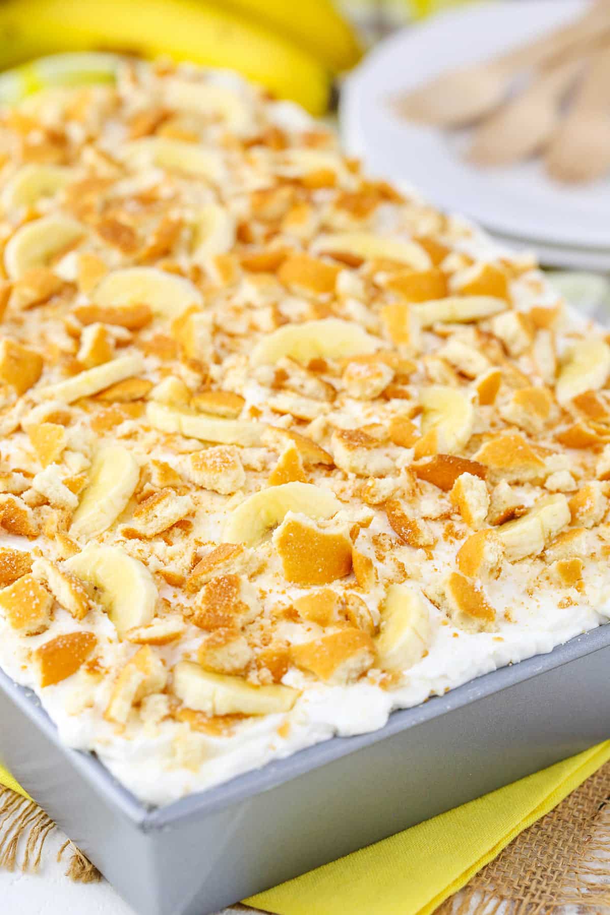 A full Banana Pudding Poke Cake in a gray cake pan on a yellow table cloth