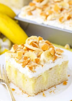 A square serving of Banana Poke Cake next to a fork on a white plate