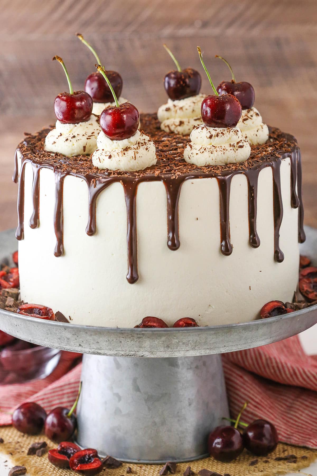 Side view of a full Black Forest Cake on a gray cake stand