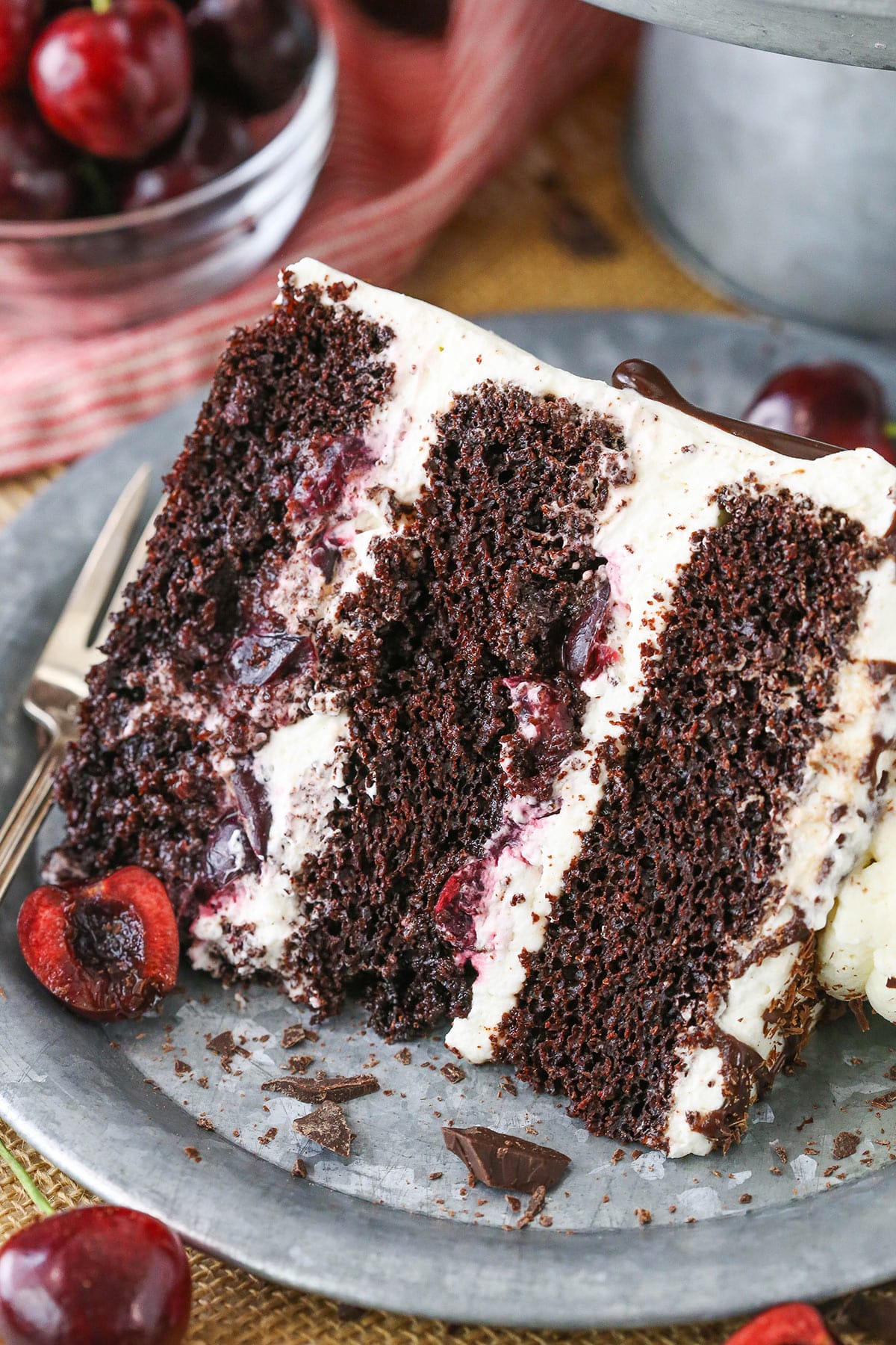 A slice of Black Forest Cake next to a silver fork on a gray plate