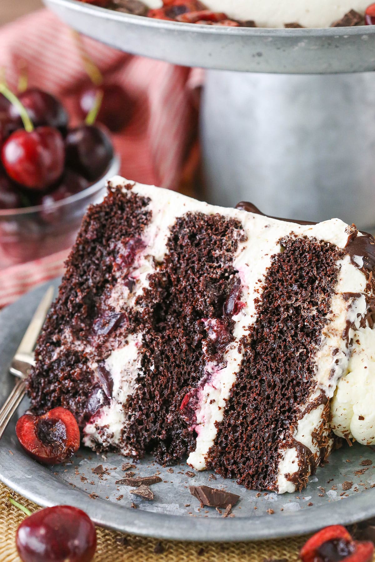 A slice of Black Forest Cake next to a silver fork on a gray plate