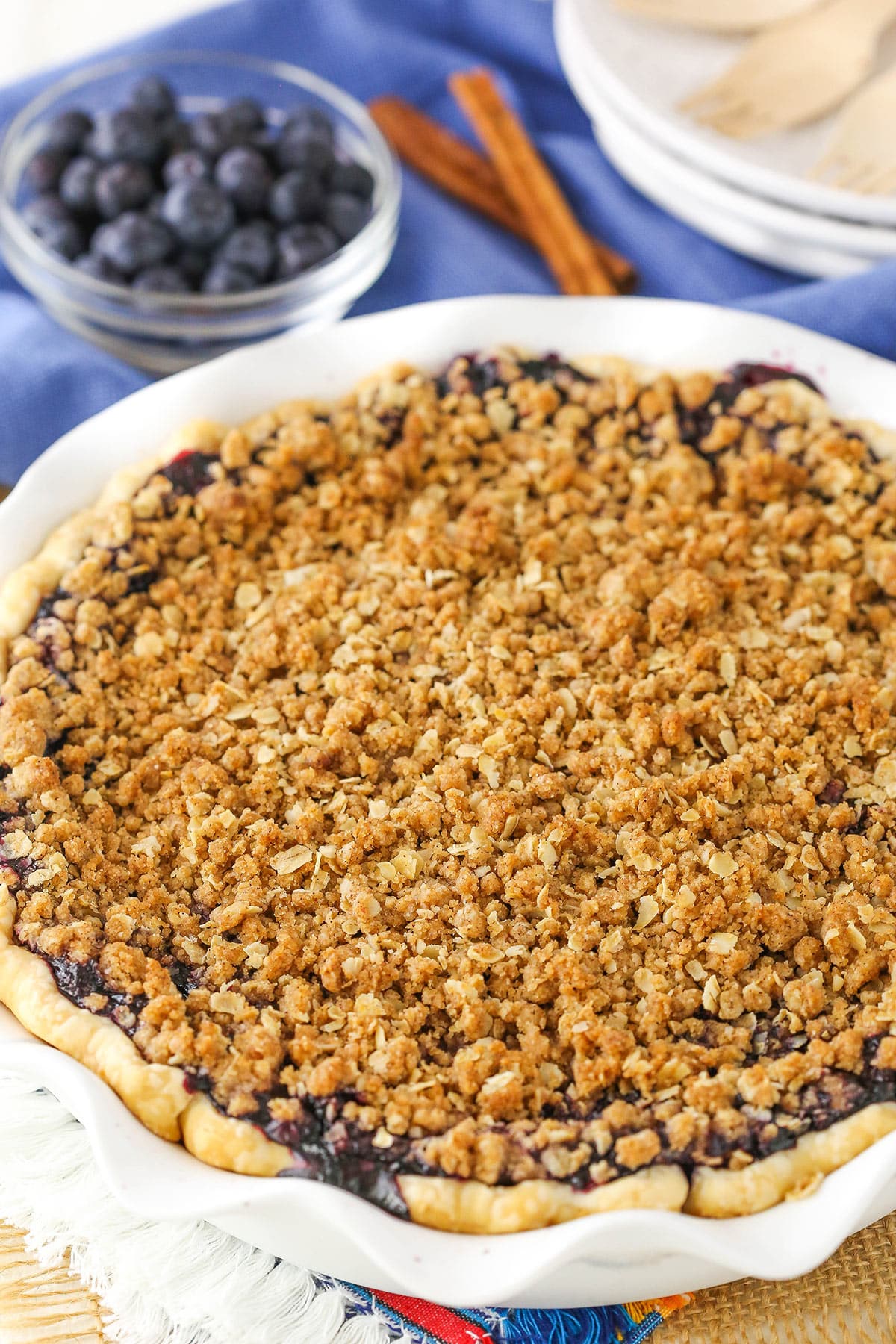 Overhead view of a full Blueberry Crumb Cheesecake Pie with a bowl of blueberries in the background