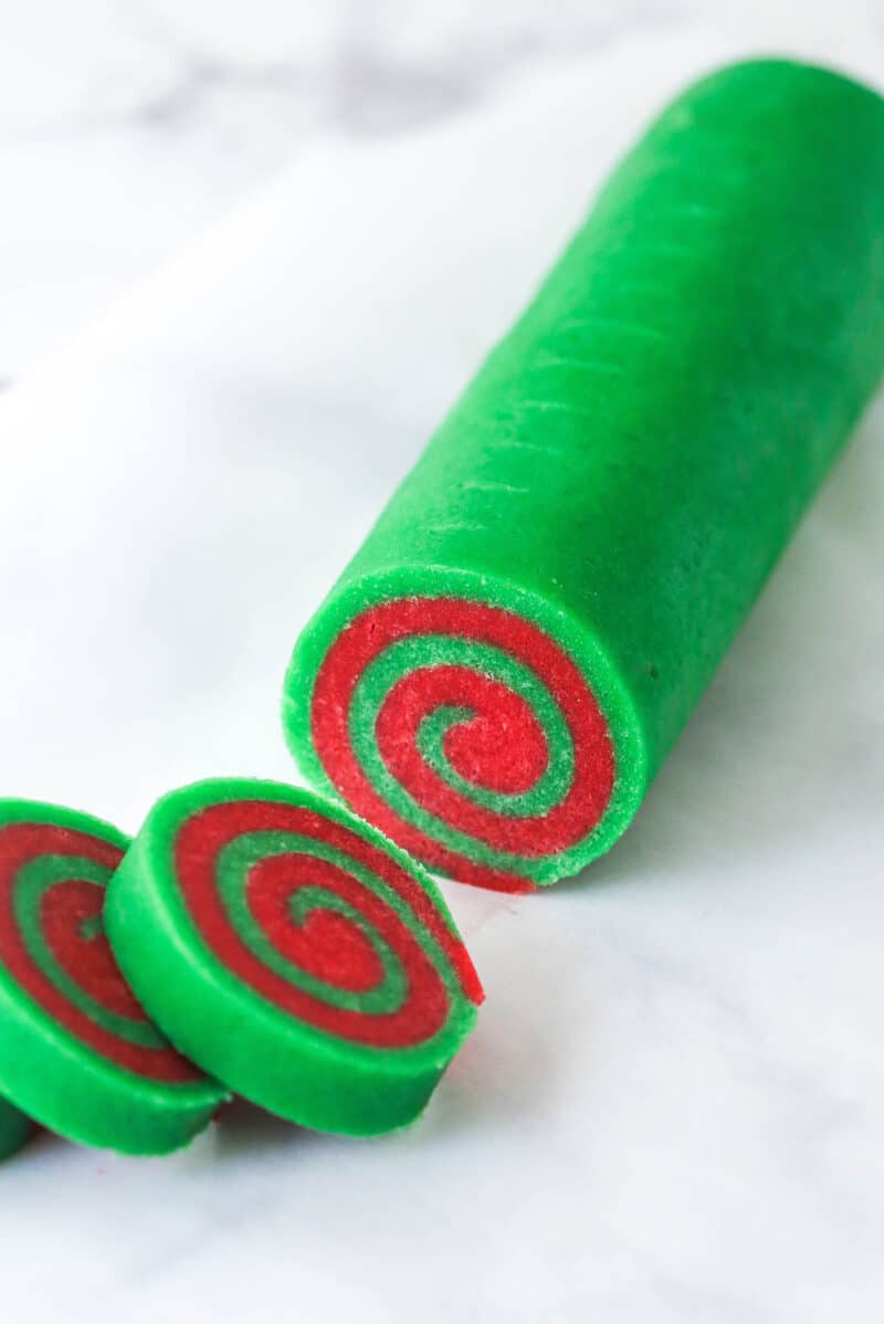 A log of Christmas pinwheel cookie dough with a few cookies sliced