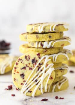 A stack of cranberry orange shortbread cookies, one leaning against the stack