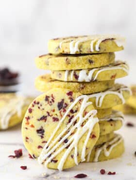 A stack of cranberry orange shortbread cookies, one leaning against the stack