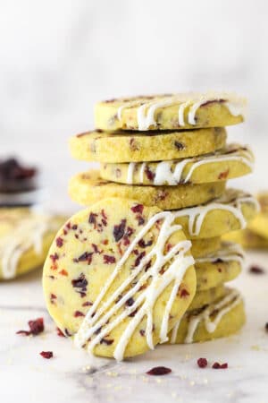 A stack of cranberry orange shortbread cookies, one leaning against the stack