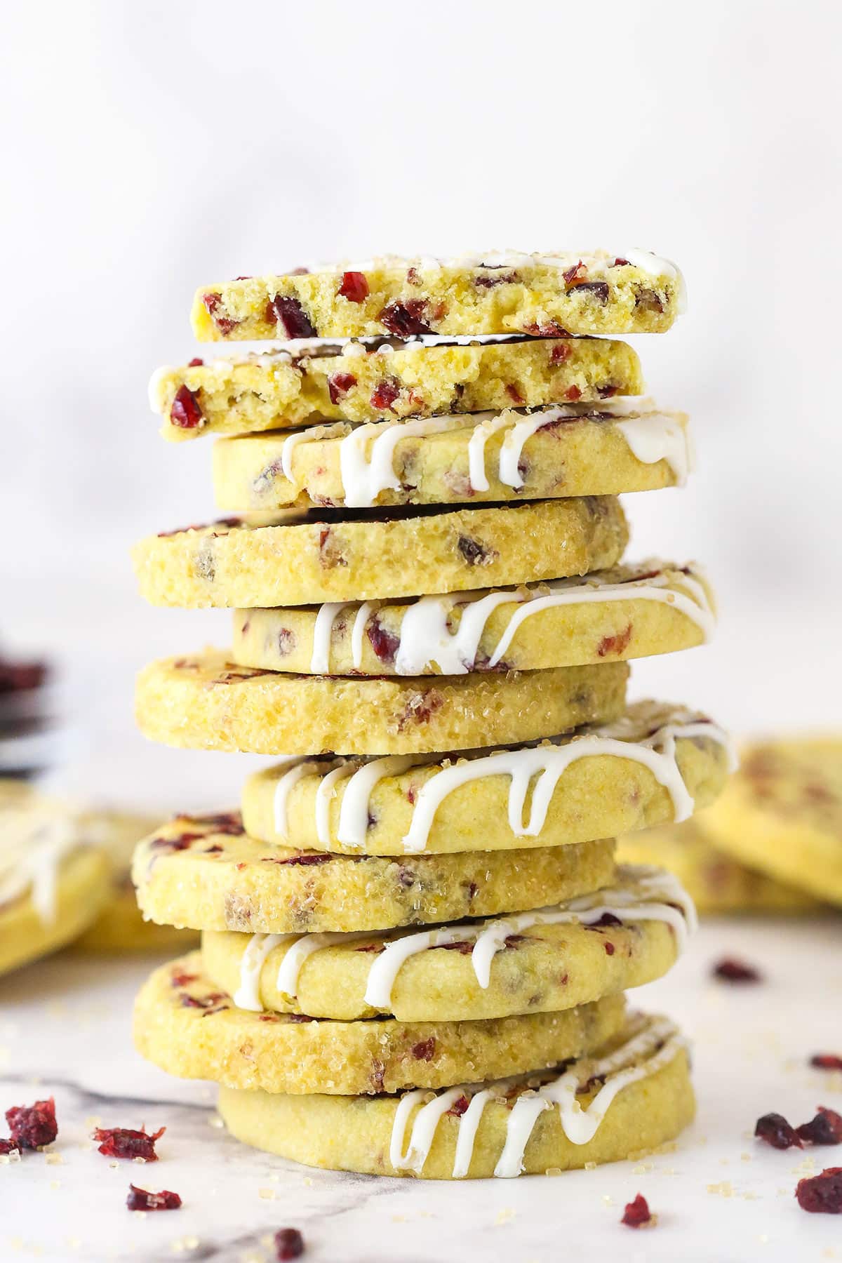 A stack of cranberry orange shortbread cookies with the top one broken in half