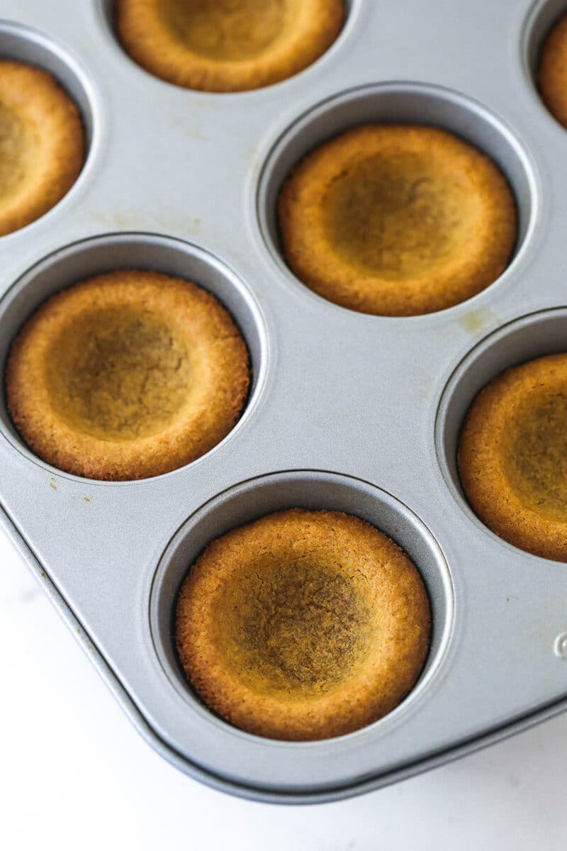 Baked gingerbread cookie cups in a baking pan.