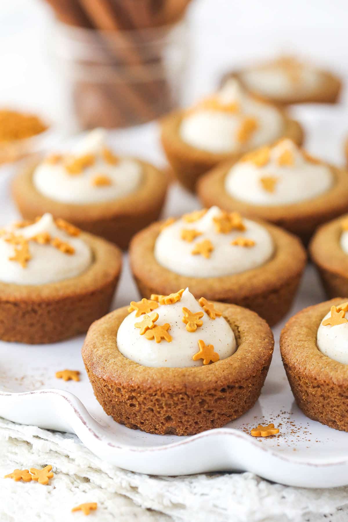 Side view of several Gingerbread Cheesecake Cookie Cups on a white platter.