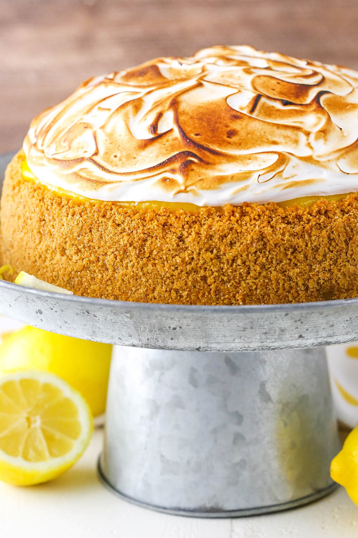 Side view of a full Lemon Meringue Cheesecake on a gray cake stand