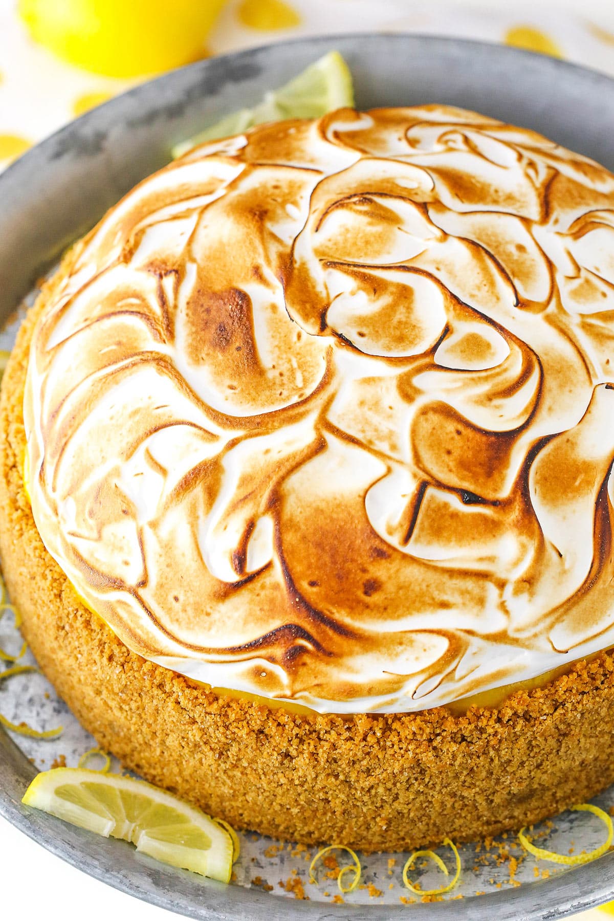 Overhead view of a full Lemon Meringue Cheesecake on a gray cake stand