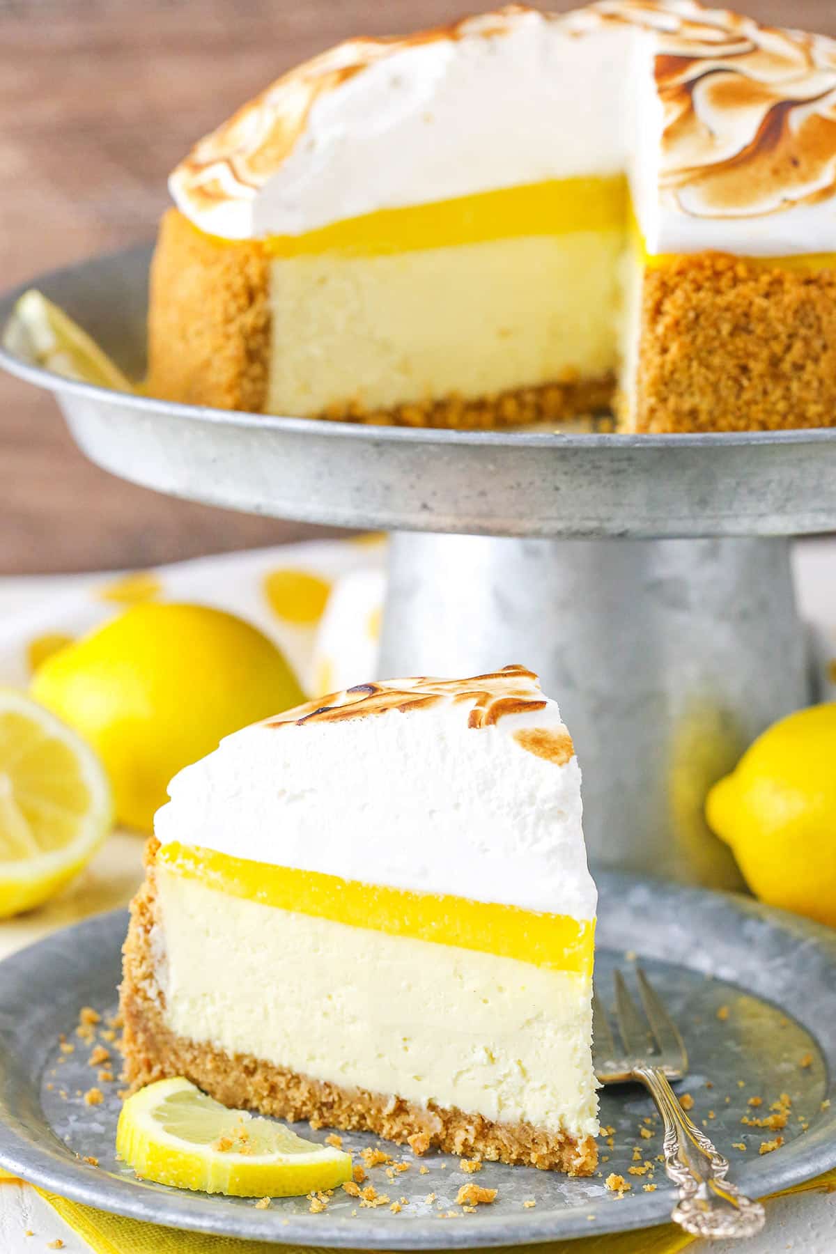 A slice of Lemon Meringue Cheesecake next to a fork on a gray plate