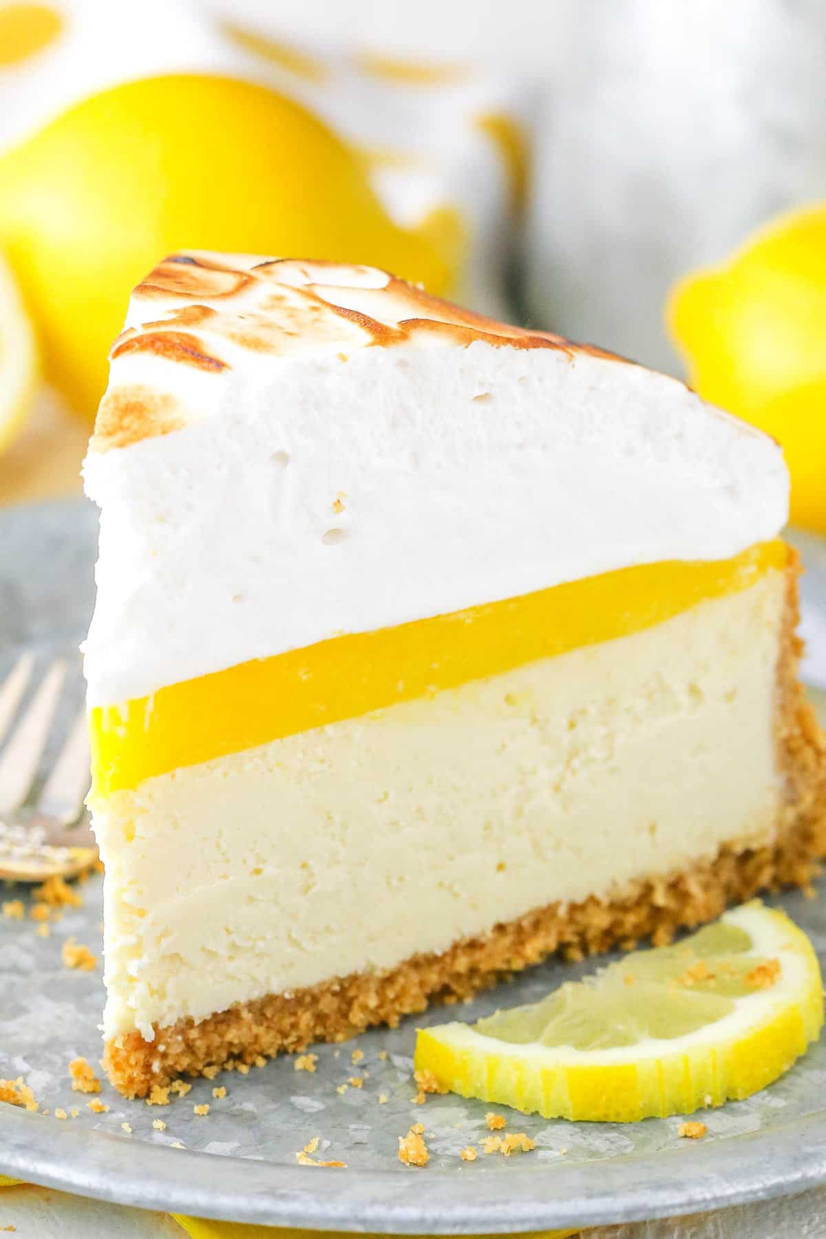 A slice of Lemon Meringue Cheesecake on a gray plate