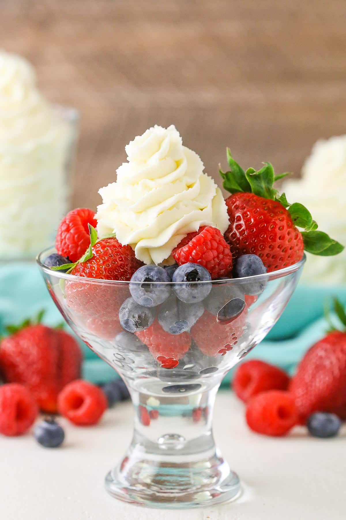 Mascarpone whipped cream with strawberries, blueberries and raspberries in a clear glass bowl