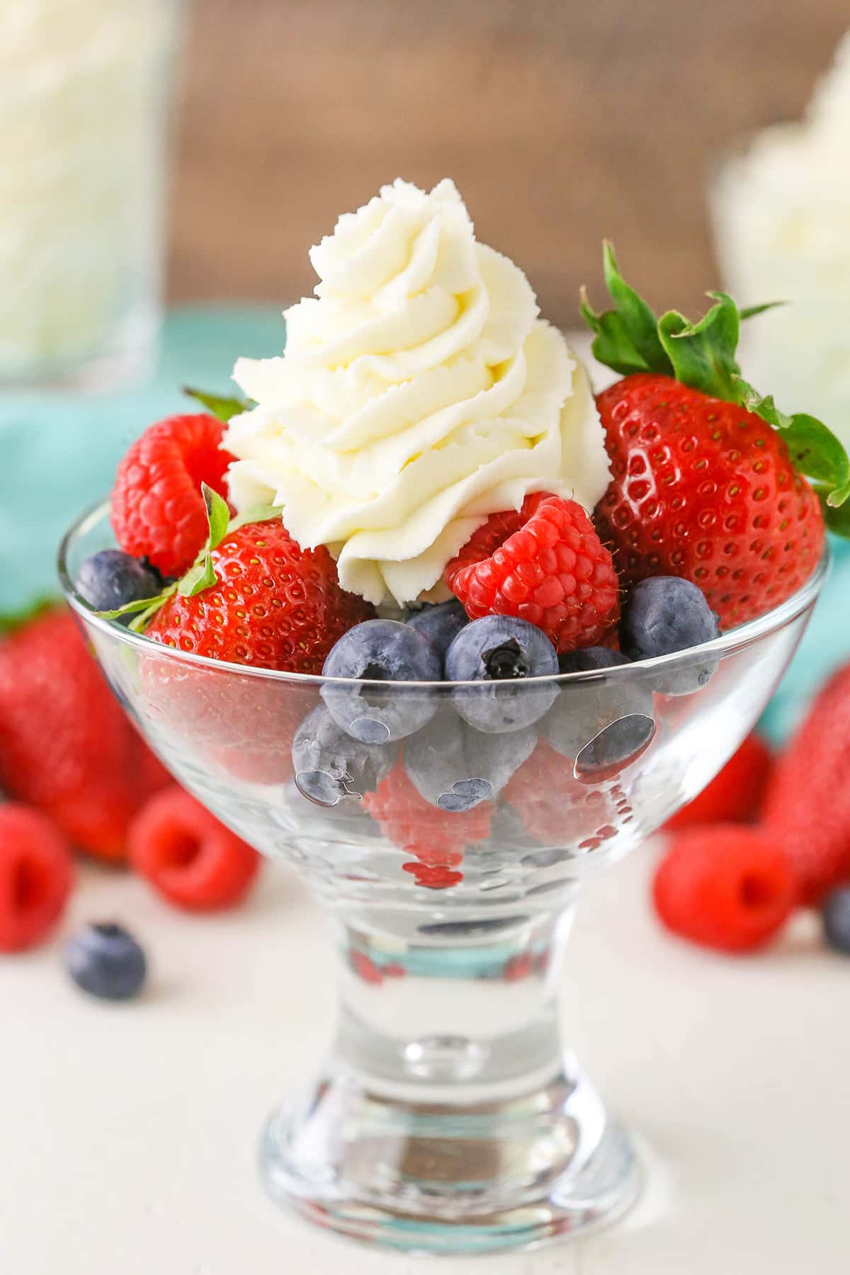 Mascarpone whipped cream with strawberries, blueberries and raspberries in a clear glass bowl