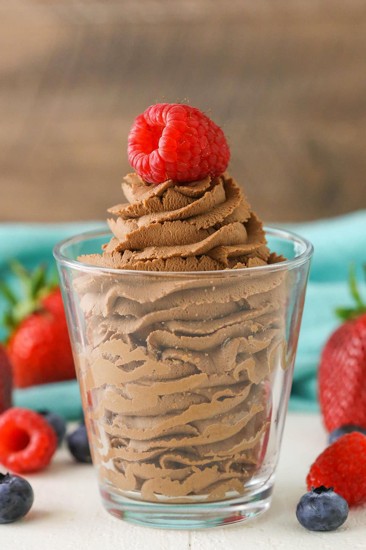 Chocolate mascarpone whipped cream with a raspberry on top in a clear glass bowl