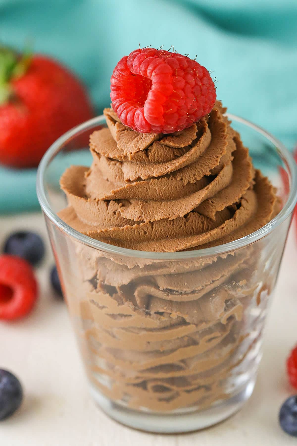 Chocolate mascarpone whipped cream with a raspberry on top in a clear glass bowl