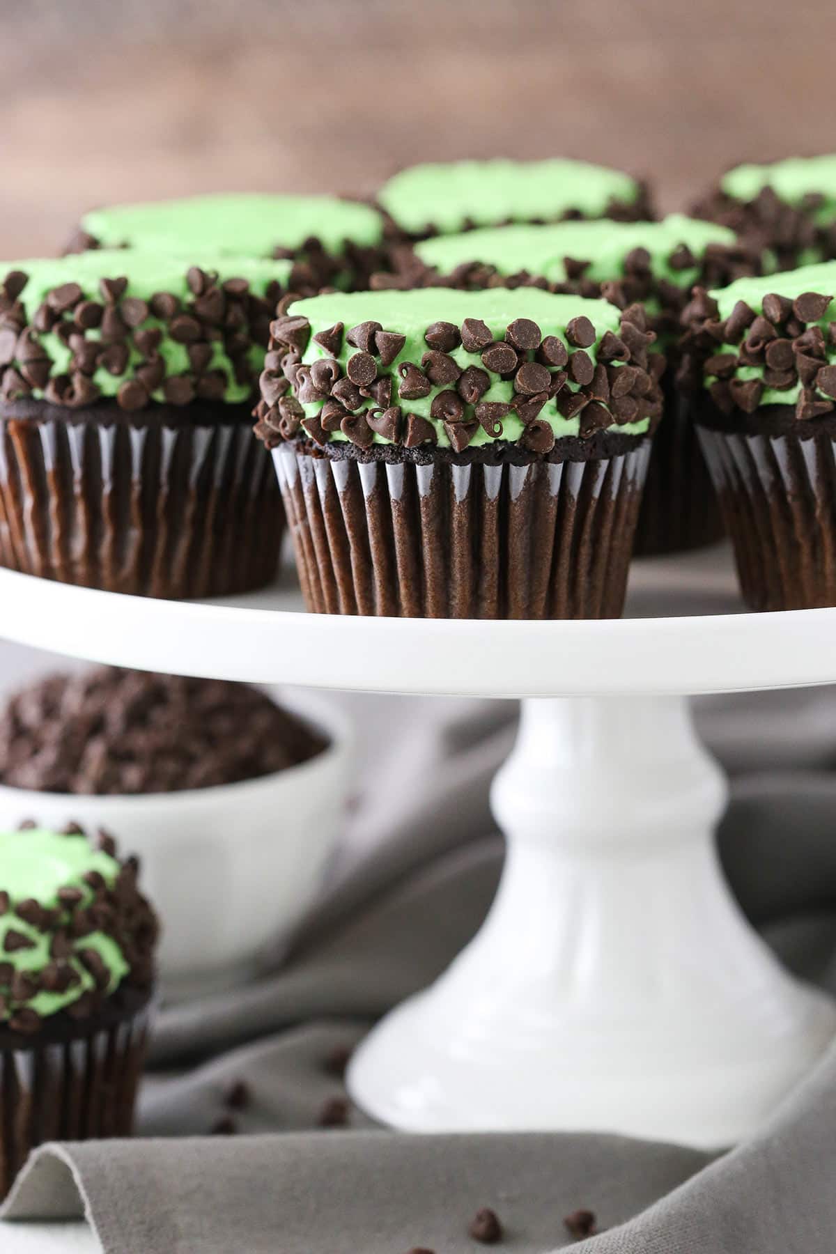 Side view of Mint Chocolate Chip Cupcakes on a white cake stand