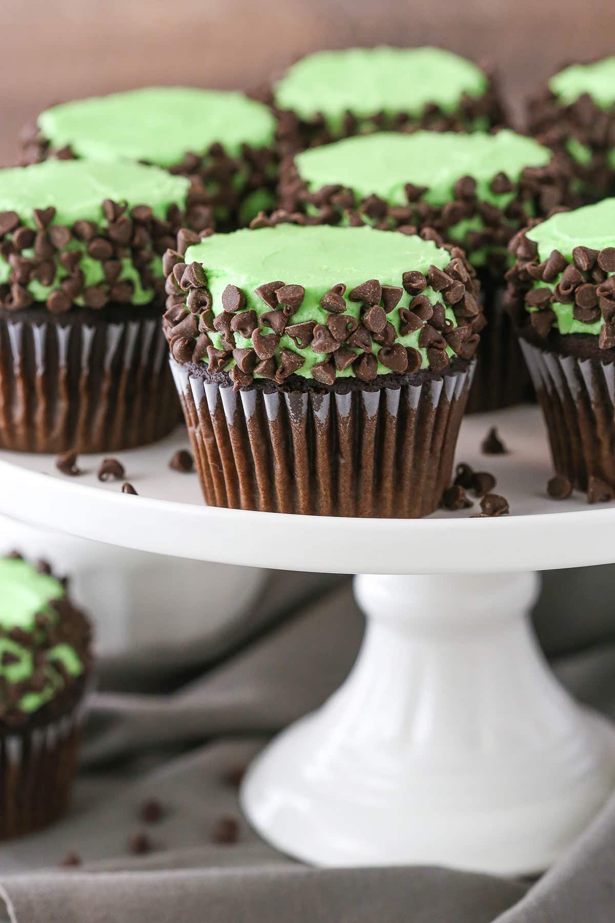 Side view of Mint Chocolate Chip Cupcakes on a white cake stand