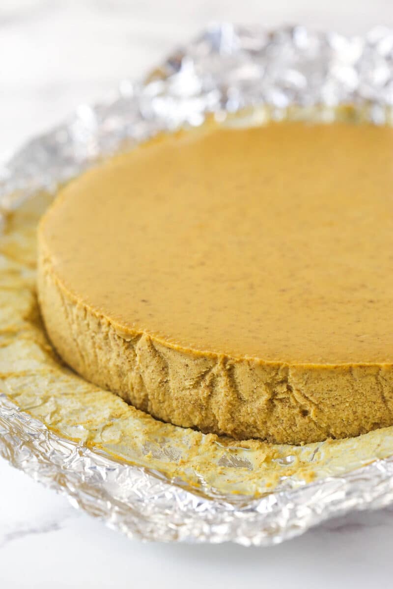 Pumpkin cheesecake round with the foil pulled off the outside edge.