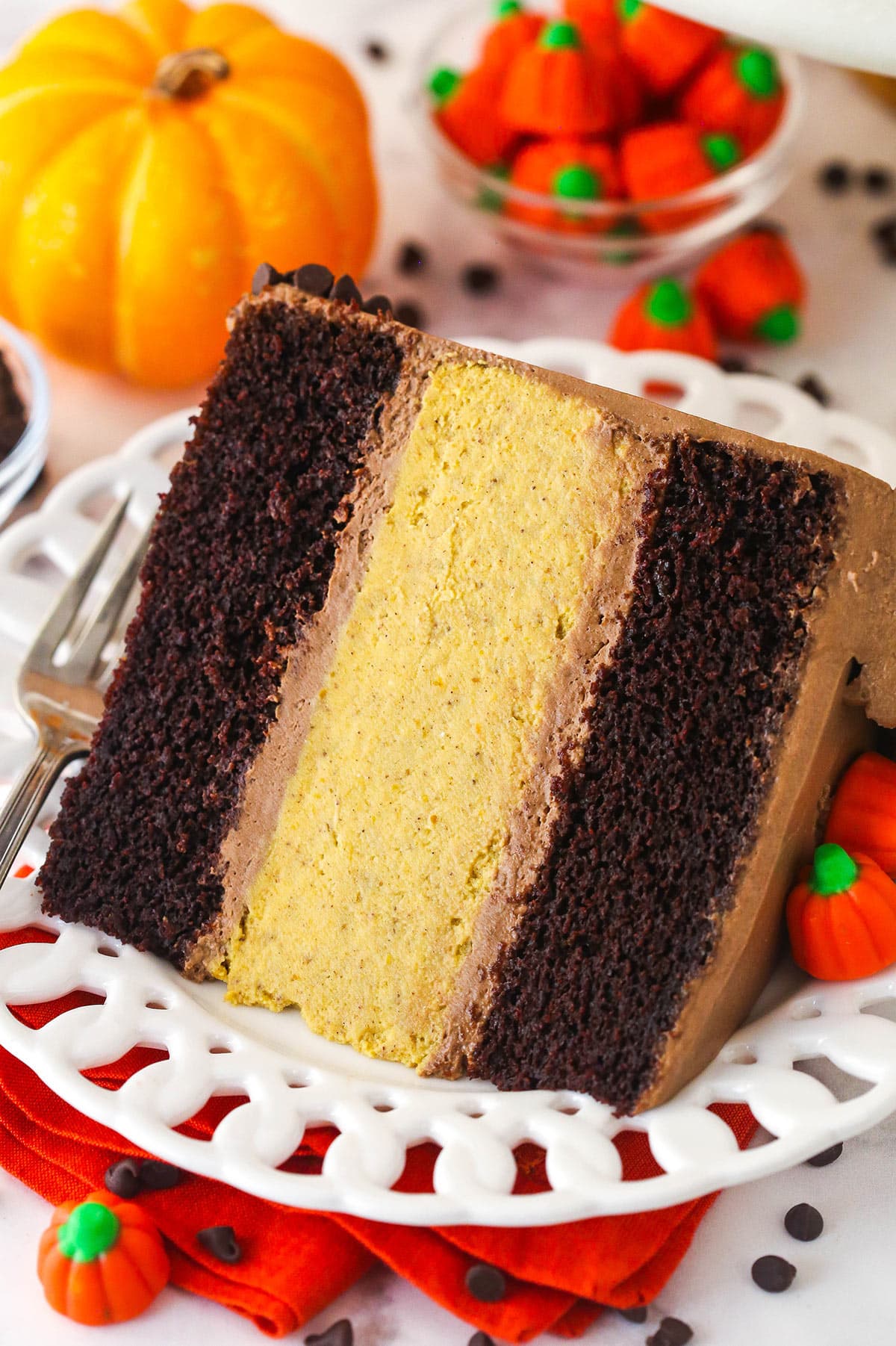 A slice of Chocolate Pumpkin Cheesecake Cake on a white plate.