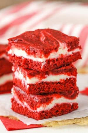 Three Red Velvet Cheesecake Swirl Brownies stacked on a white napkin