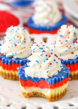 A Red White and Blue Mini Cheesecake with a bite removed on a white plate