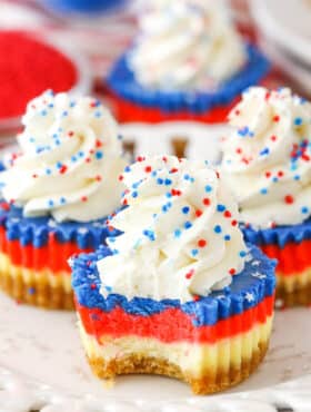 A Red White and Blue Mini Cheesecake with a bite removed on a white plate