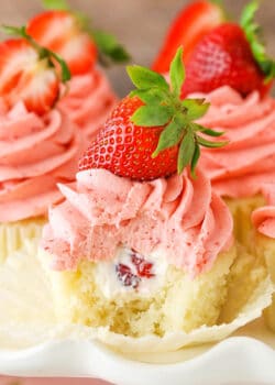 A Strawberries and Cream Cupcake with a bite removed