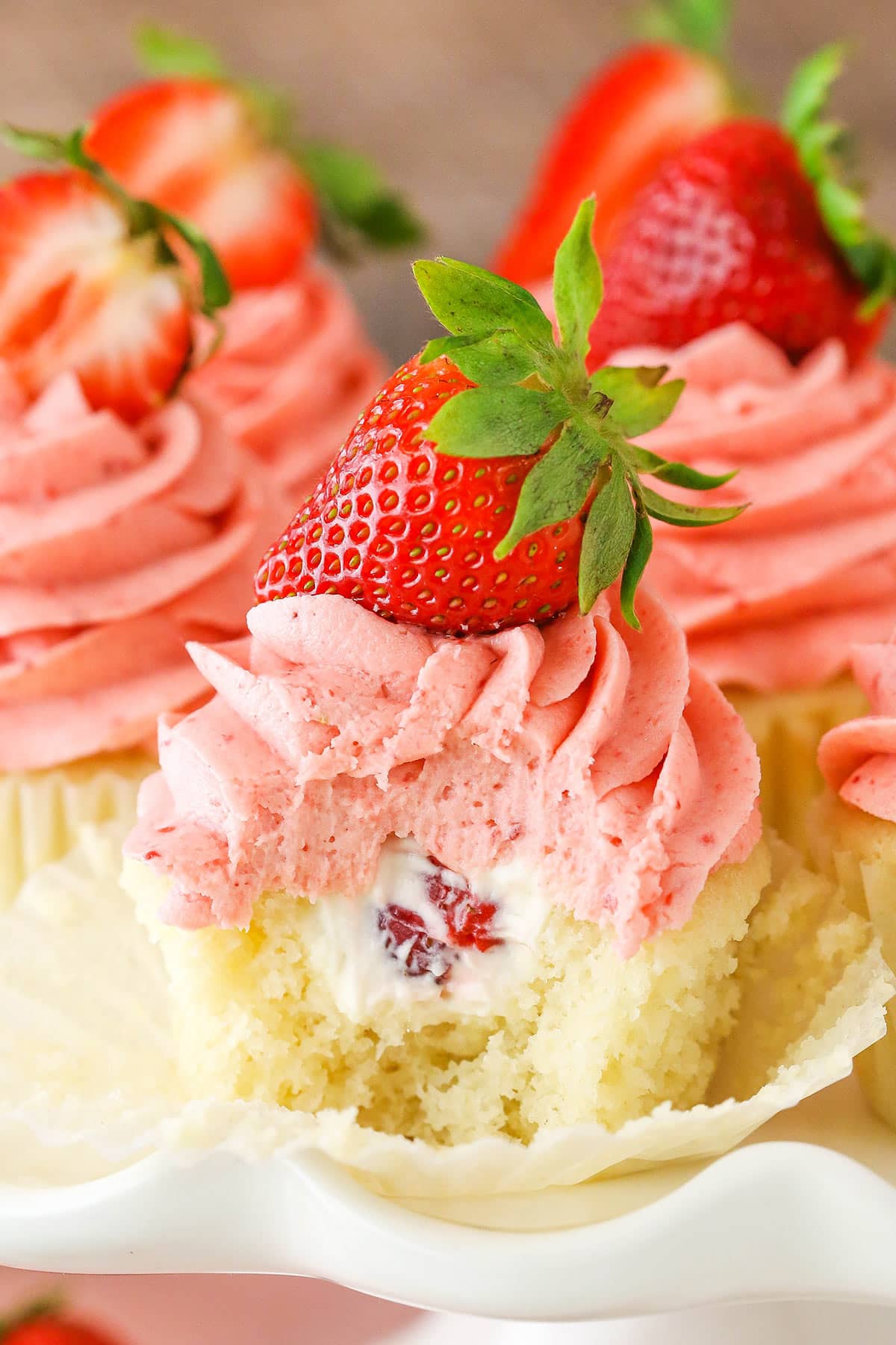 A Strawberries and Cream Cupcake with a bite removed