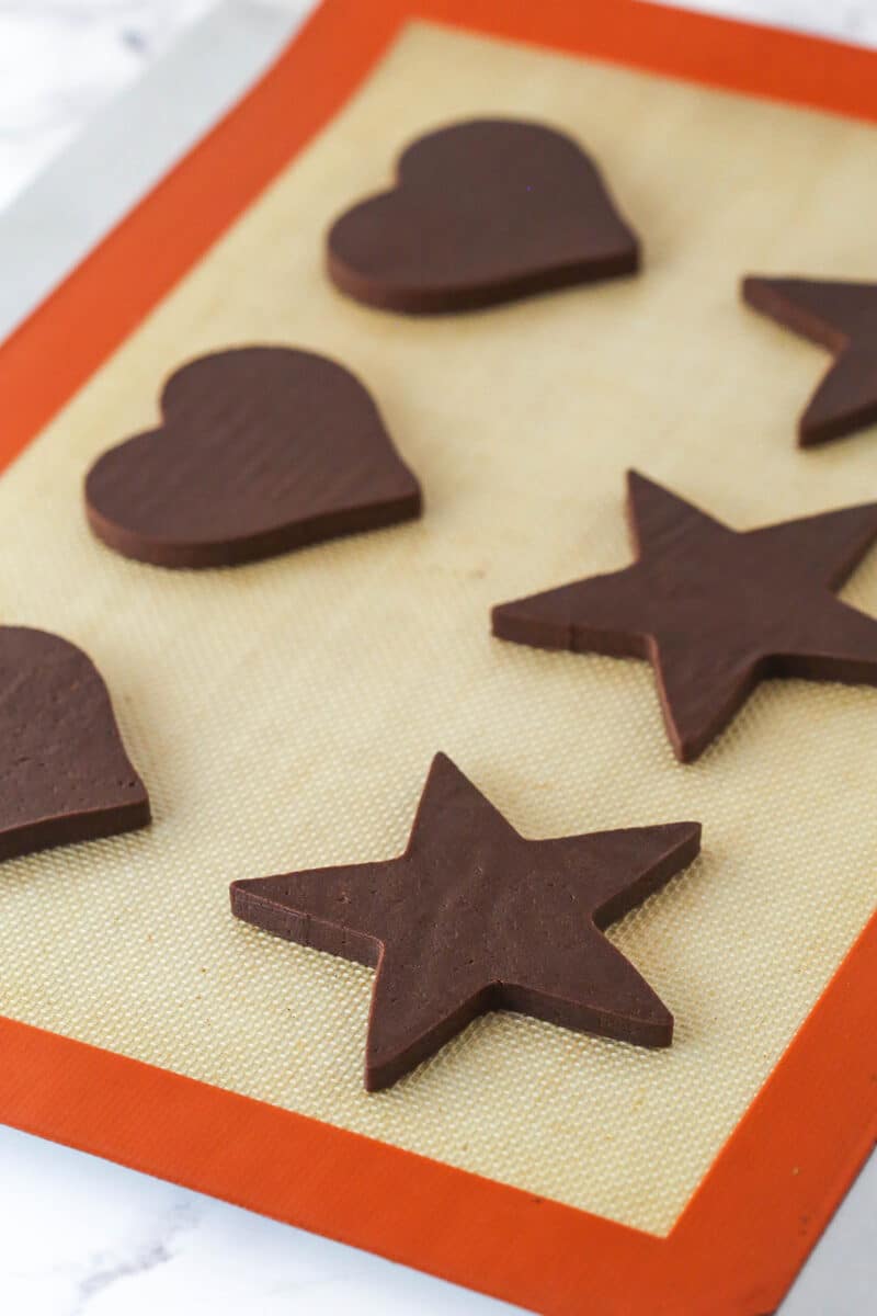 Unbaked cut out chocolate cookies on a baking sheet