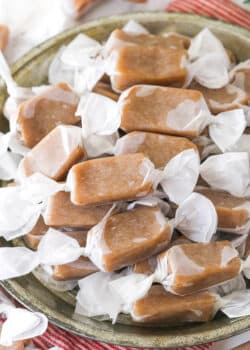 homemade caramels wrapped in wax paper in grey dish