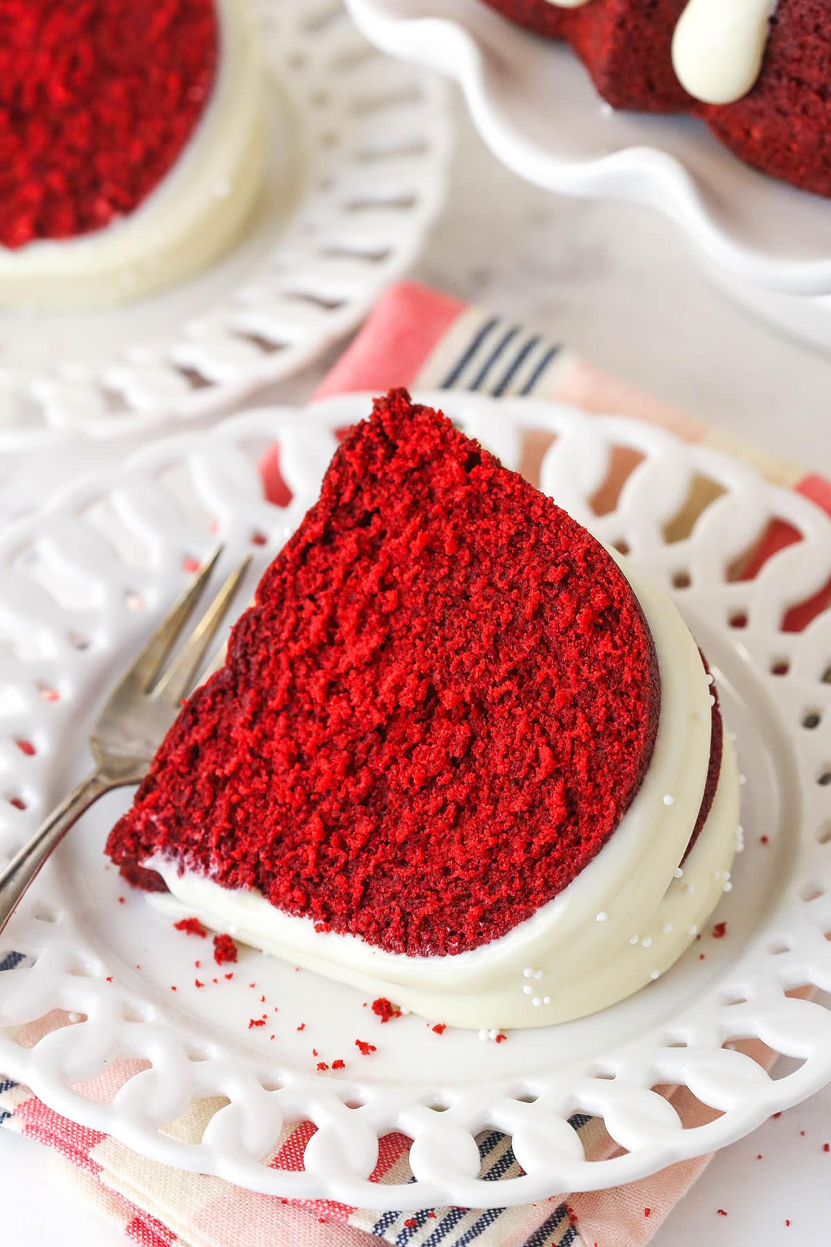 Overhead view of a slice of red velvet bndt cake on a white plate