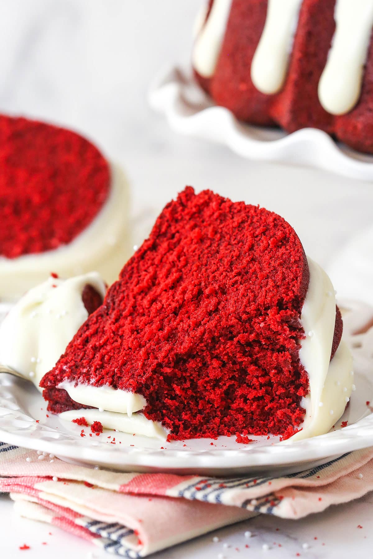 A plate with a slice of red velvet bundt cake with a piece missing