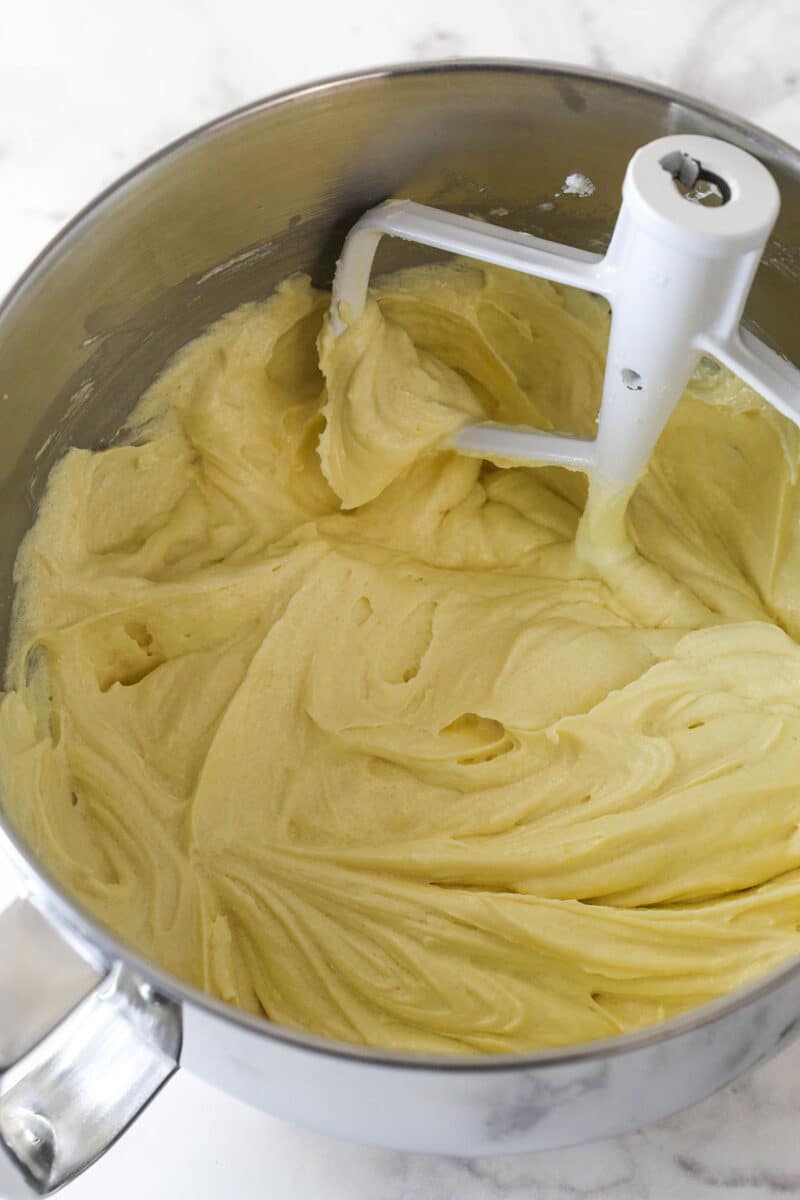 Eggs mixed into creamed butter, sugar, and oil in a mixing bowl.