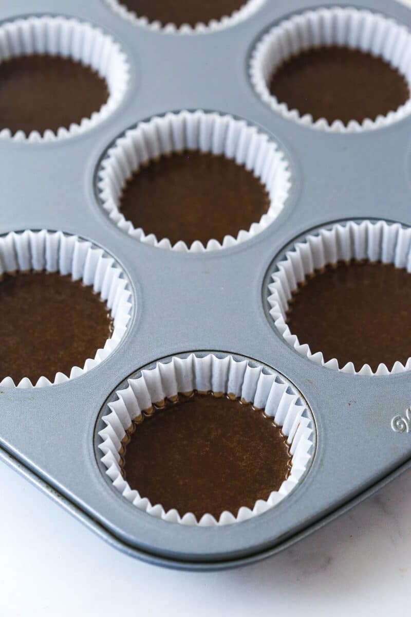 Filling cupcake liners halfway with chocolate cupcake batter.