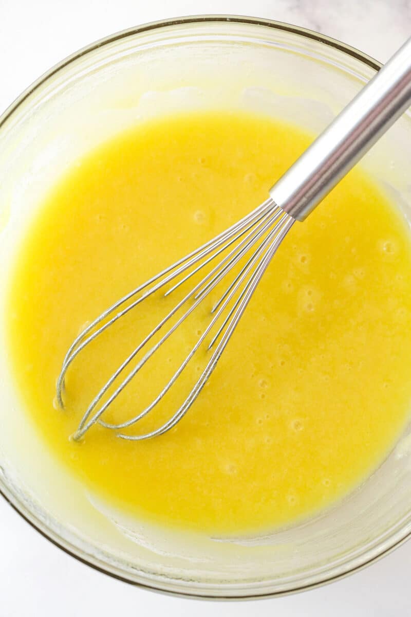 Mixing eggs into oil, sugar, and vanilla.