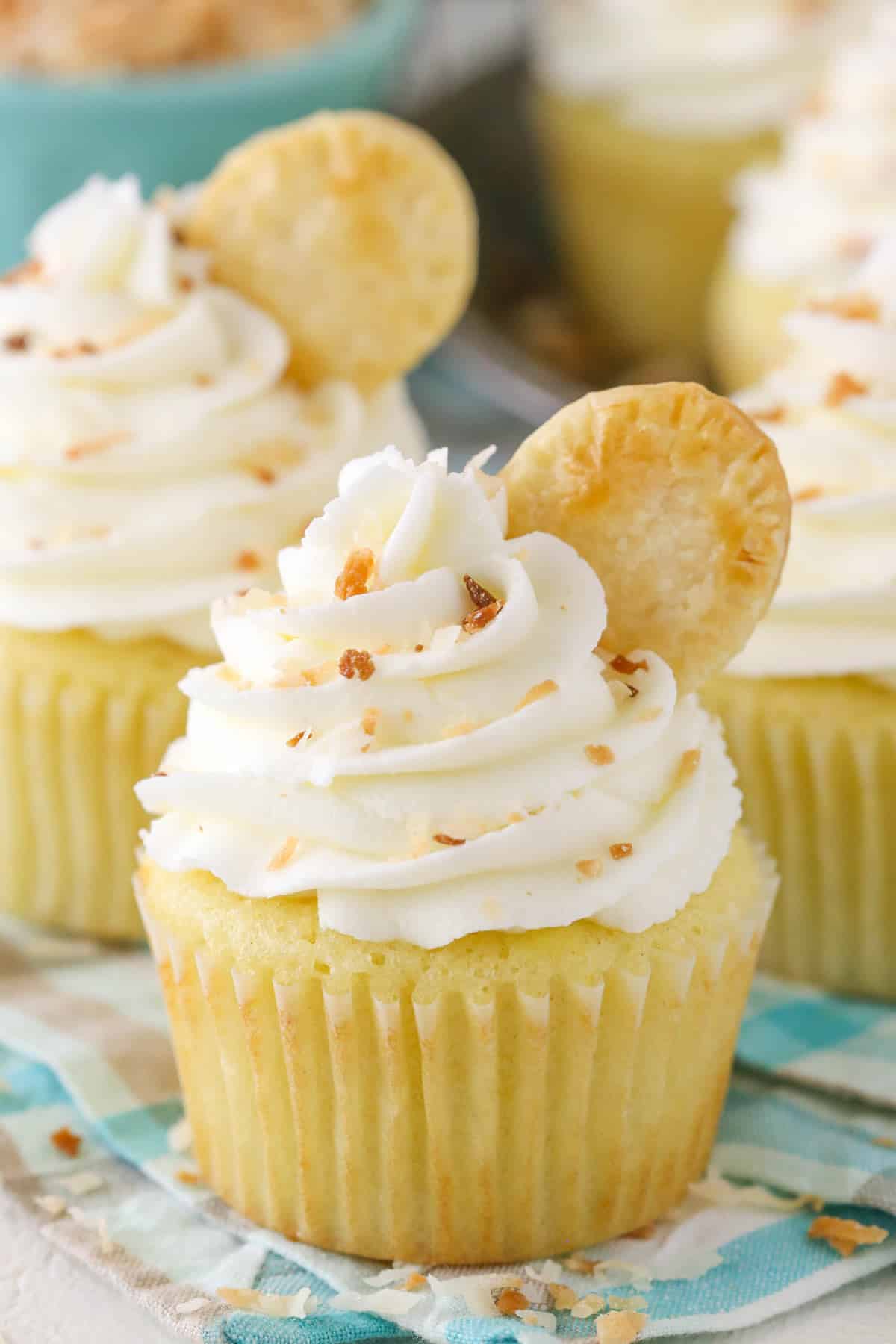 Close up of a coconut cream pie cupcake on a teal cloth.